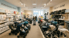 A store aisle filled with multiple rows of baby strollers and prams with shoppers browsing